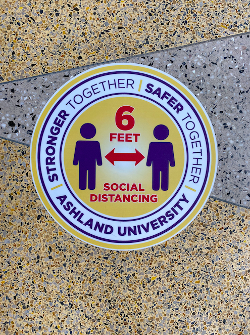 Floor signs reminding students to stay six feet apart can be found in many buildings
