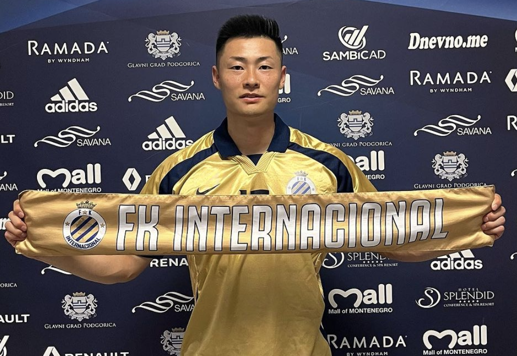 Haruki Kimura stands with an FK Internacional banner after signing his contract with the club.
