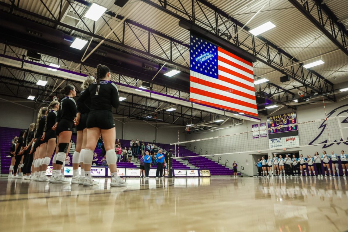 The Ashland University Eagle volleyball team stands at center court for the national anthem against the Yellow Jackets.
