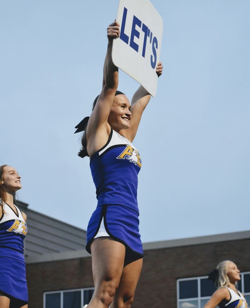 Harris puts up a cheer for the sideline cheer team during a football game.