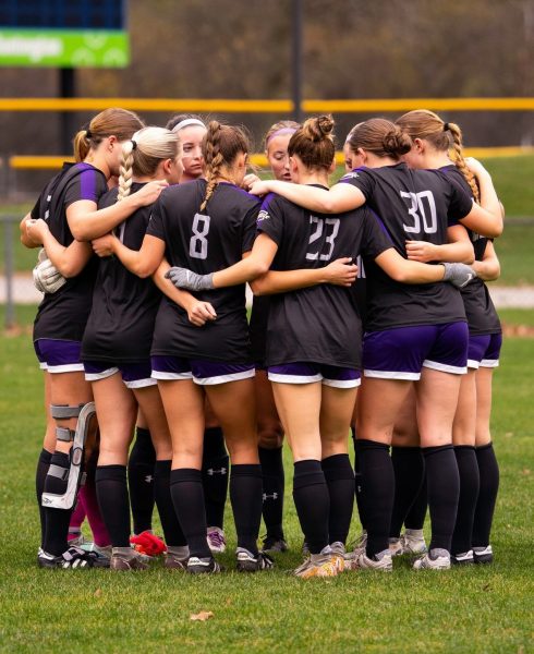 AU women's soccer team huddled together.