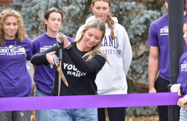 Sarah Watson cutting ribbon at unveiling of suicide prevention bench.