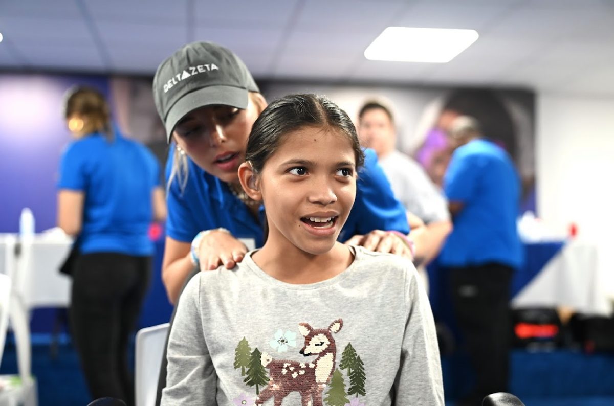 Pacey Chrastina fitting a hearing aid for a young girl